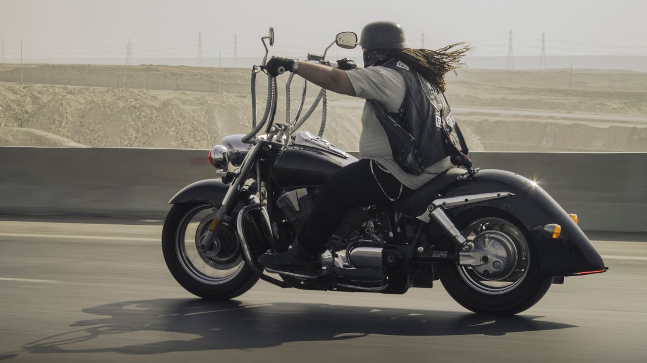 A biker rides a motorcycle on a desert highway, capturing freedom and adventure.